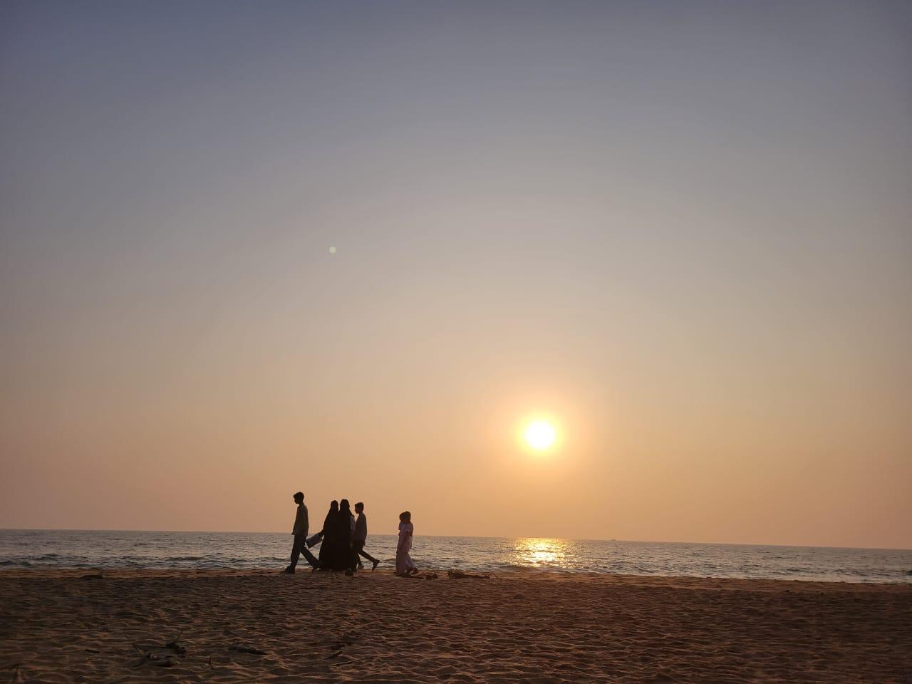 Silhouettes walking on the beach at sunset, Kannur